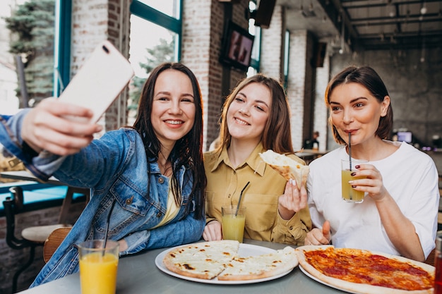 Amigas comiendo pizza en un bar a la hora del almuerzo