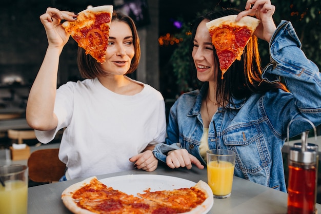 Foto gratuita amigas comiendo pizza en un bar a la hora del almuerzo