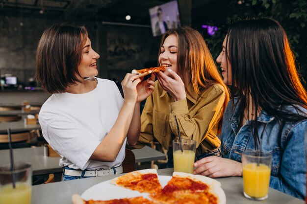 Amigas comiendo pizza en un bar a la hora del almuerzo