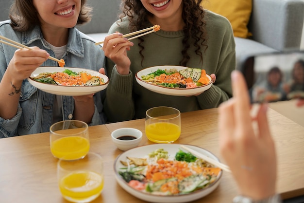 Amigas comiendo platos de mariscos con salmón juntos