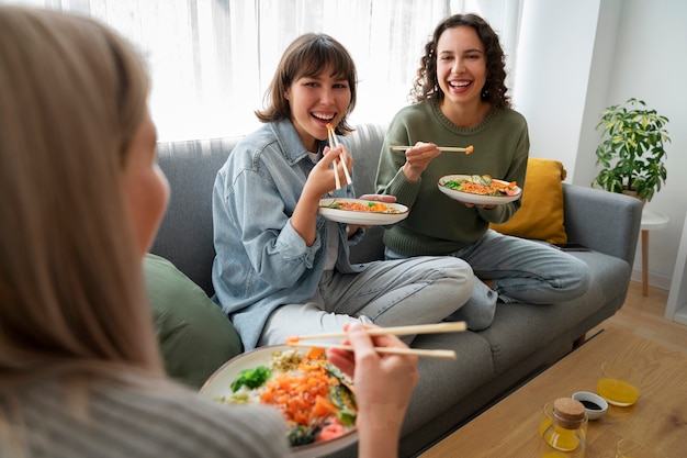 Amigas comiendo platos de mariscos con salmón juntos