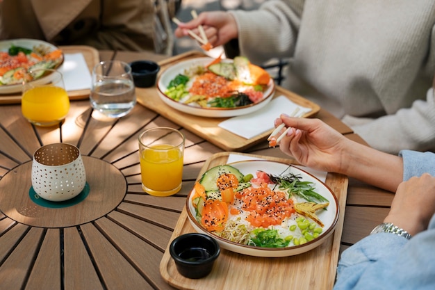 Amigas comiendo platos de mariscos con salmón juntos