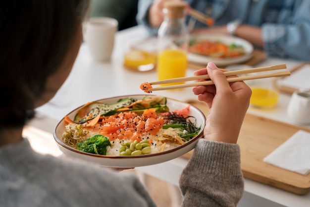 Amigas comiendo platos de mariscos con salmón juntos