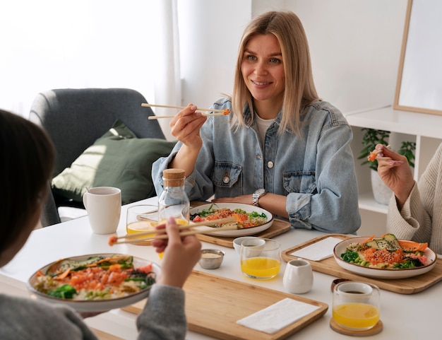 Amigas comiendo platos de mariscos con salmón juntos