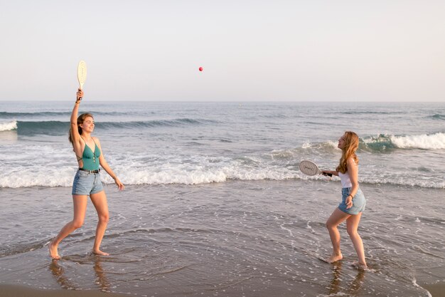 Amigas disfrutando jugando con tenis en la orilla del mar
