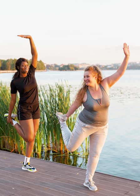 Amigas estirando juntos por el lago