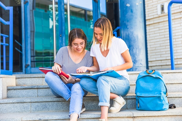 Foto gratuita amigas estudiando en los pasos de la universidad