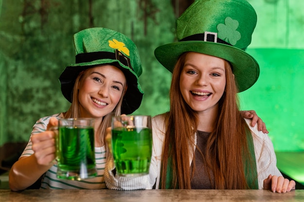 Foto gratuita amigas felices celebrando st. día de patrick junto con bebidas