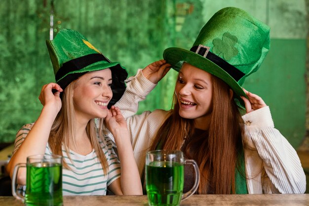 Amigas felices celebrando st. patrick's day juntos en el bar