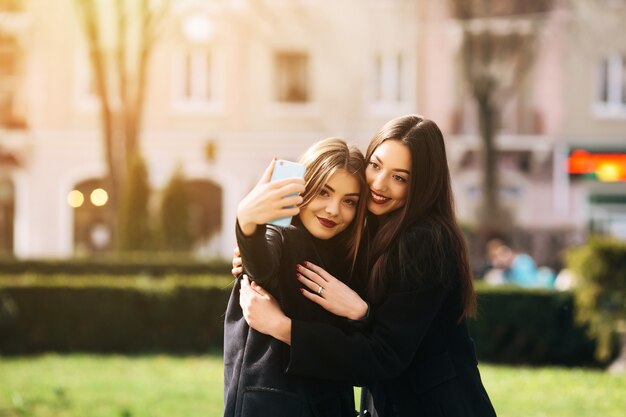 Amigas felices tomándose una foto en la calle