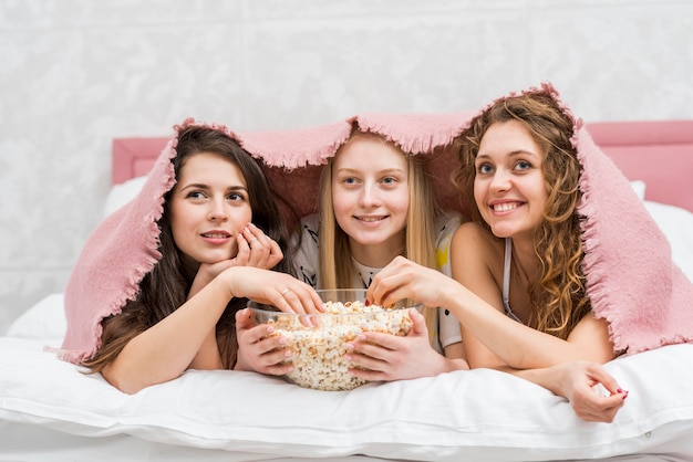 Foto gratuita amigas en fiesta de pijamas comiendo palomitas