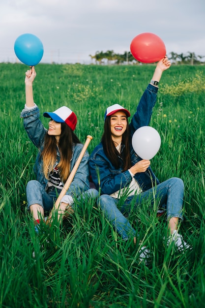 Foto gratuita amigas con globos en tapas de colores riendo en el parque