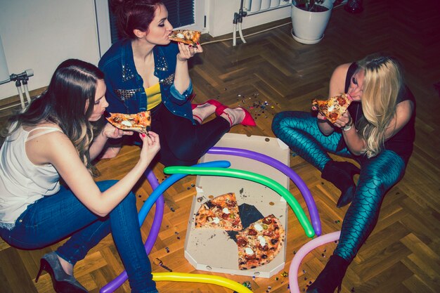 Amigas hambrientas comiendo pizza en la fiesta