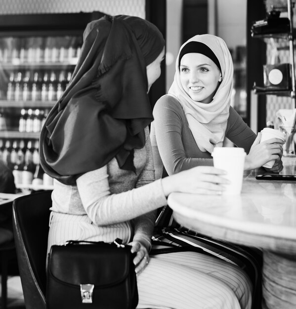 Amigas islámicas disfrutando y hablando en la cafetería.