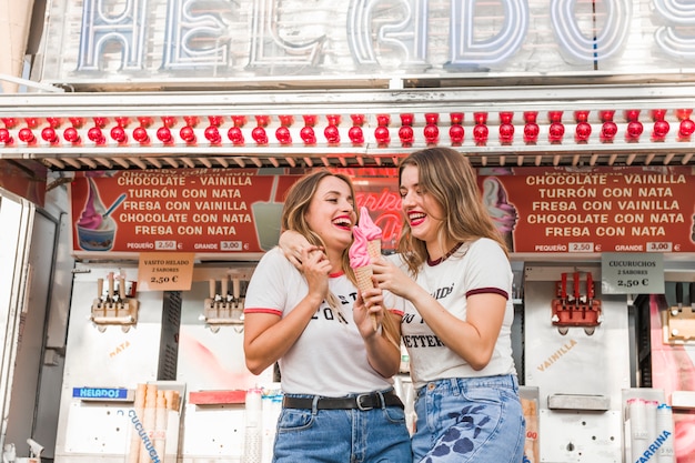 Amigas jóvenes comiendo helado en el parque de atracciones