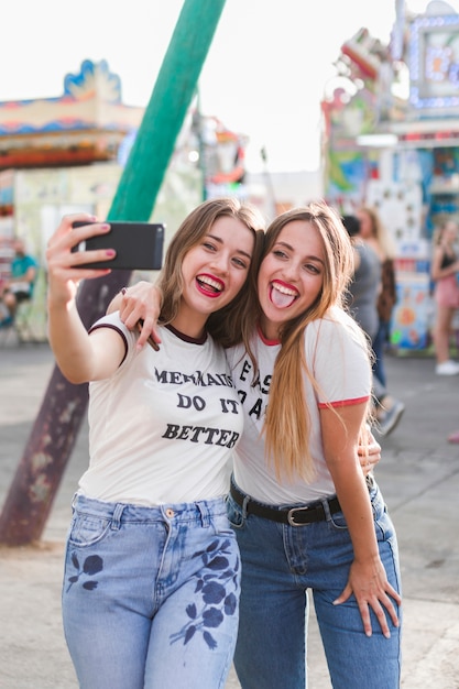 Amigas jóvenes haciendo un selfie en el parque de atracciones