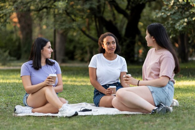 Amigas juntas en el parque con café