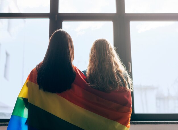 Amigas lesbianas envueltas en bandera LGBT