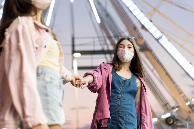 Amigas con máscaras médicas en el parque de atracciones