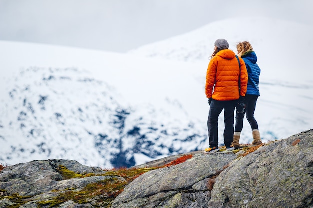 Amigas de pie en la cima de una montaña rocosa cubierta de nieve