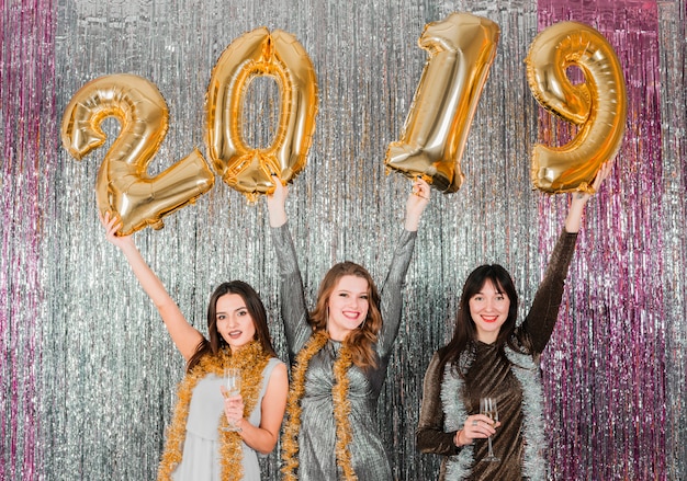 Amigas posando con globos dorados en fiesta de año nuevo