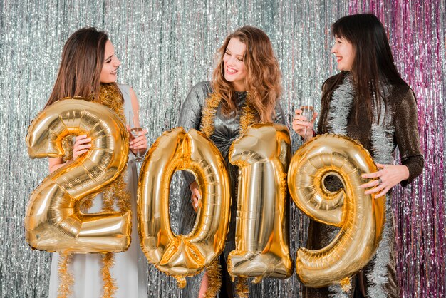Amigas posando con globos dorados en fiesta de año nuevo