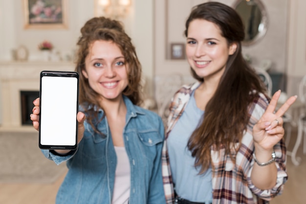 Amigas posando con un smartphone