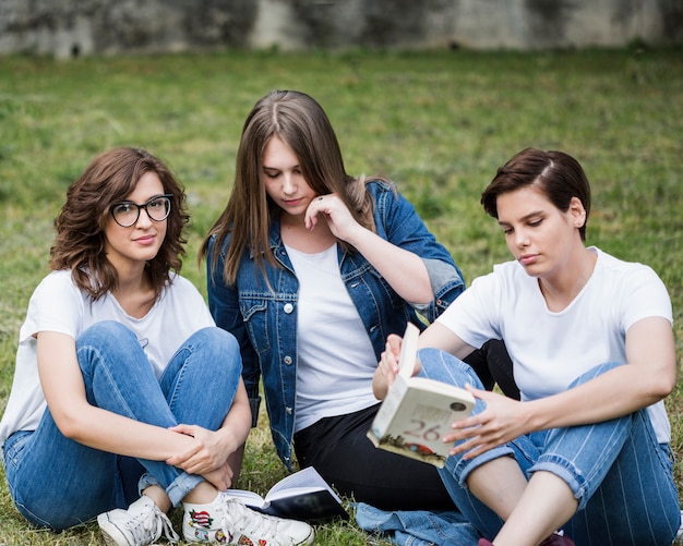 Amigas relajantes sentado en césped