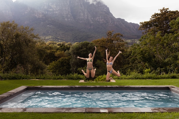 Amigas saltando en la piscina en el patio trasero