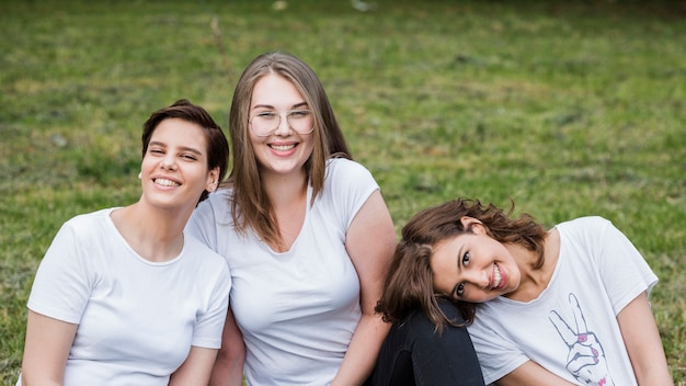 Amigas sentada en la hierba sonriendo