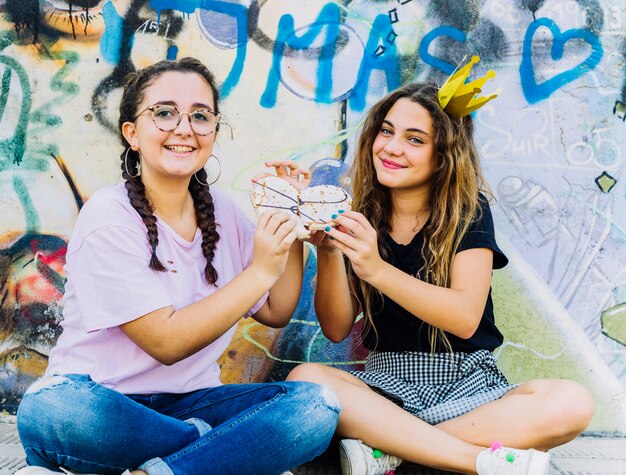 Amigas sentadas con globos y hojaldre de cumpleaños