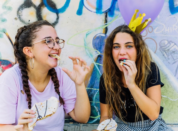 Amigas sentadas con globos y hojaldre de cumpleaños