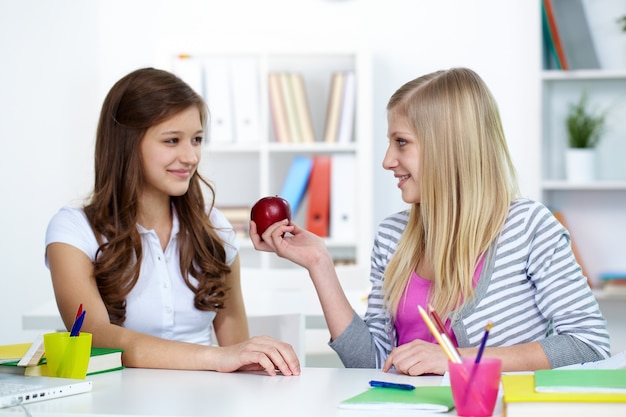 Amigas sonriendo con una manzana