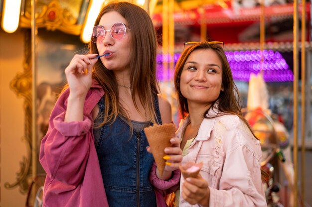 Amigas sonrientes con gafas de sol en el parque de atracciones