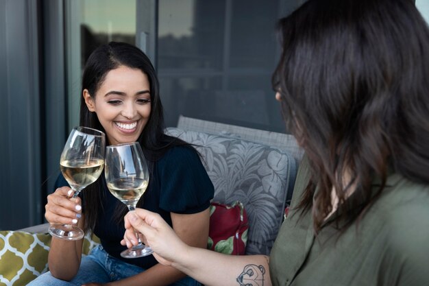 Amigas sonrientes pasar tiempo juntos y beber vino en una terraza