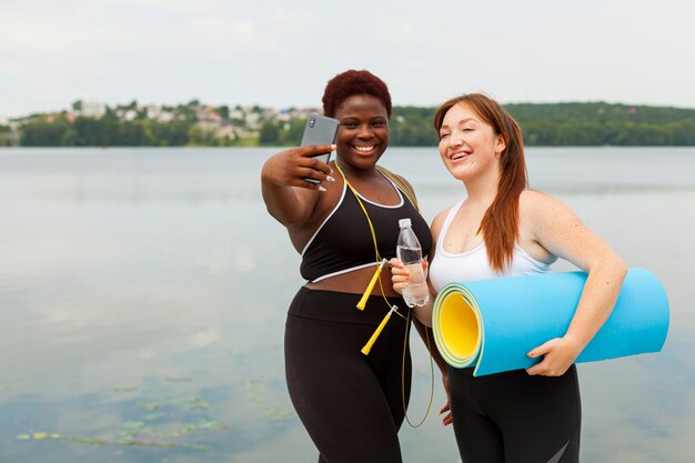 Amigas sonrientes tomando selfie al aire libre mientras hace ejercicio