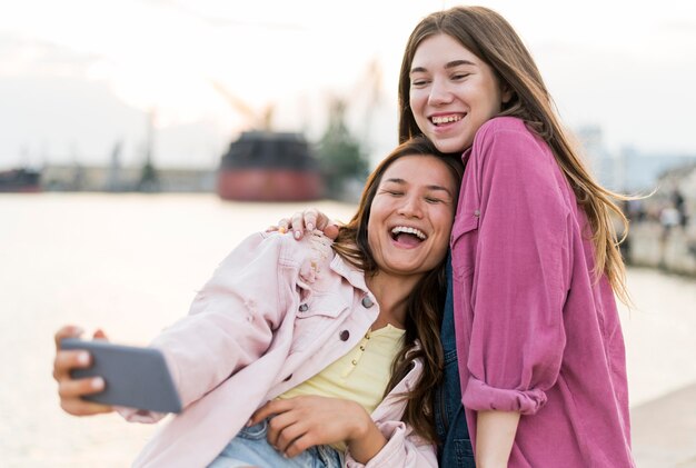 Amigas sonrientes tomando selfie junto al lago