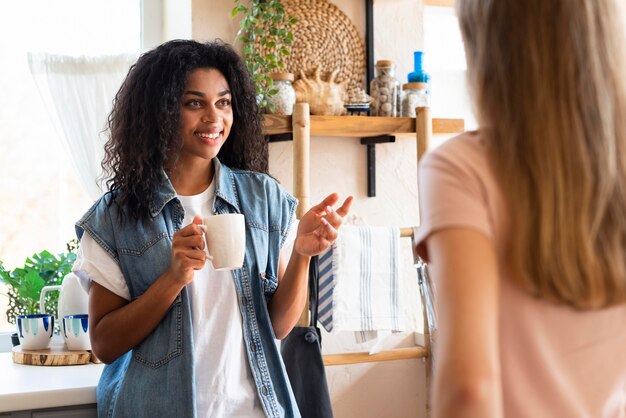 Amigas tener una conversación tomando un café en la cocina