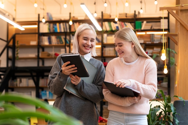 Amigas tomando libros de una biblioteca para usar en una sesión de estudio