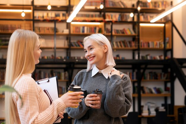 Amigas tomando libros de una biblioteca para usar en una sesión de estudio