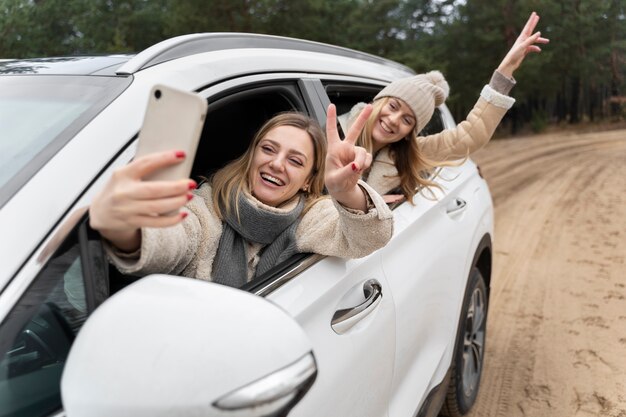 Amigas tomando un selfie fuera del auto de la ventana