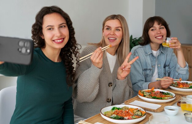 Amigas tomando selfie mientras comen un plato de mariscos con salmón