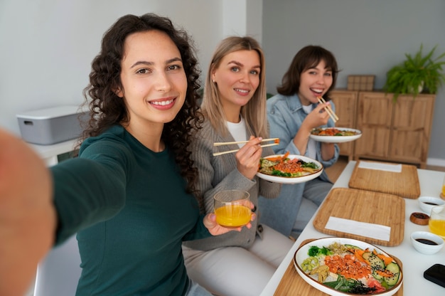 Amigas tomando selfie mientras comen un plato de mariscos con salmón