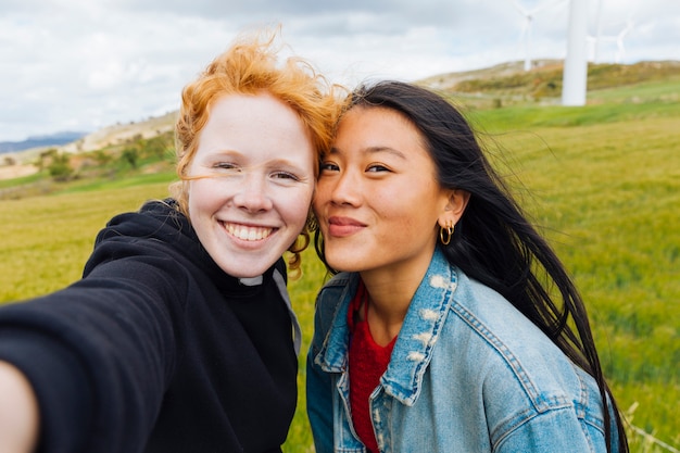 Foto gratuita amigas tomando selfie en parque eólico