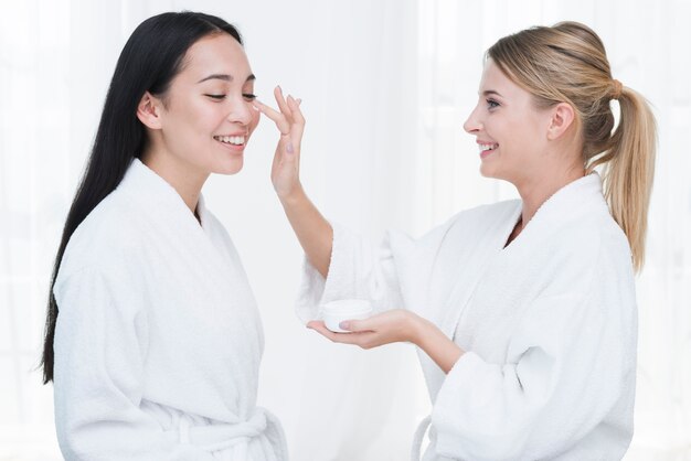 Amigas usando crema de belleza en un spa