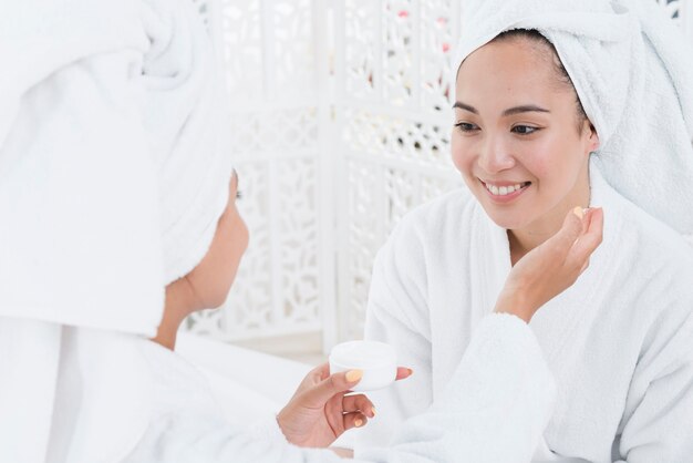 Amigas usando crema de belleza en un spa