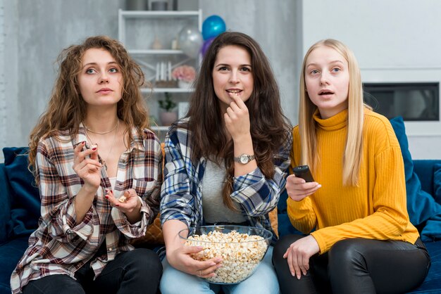 Amigas viendo una película mientras comen palomitas