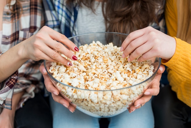 Amigas viendo una película mientras comen palomitas