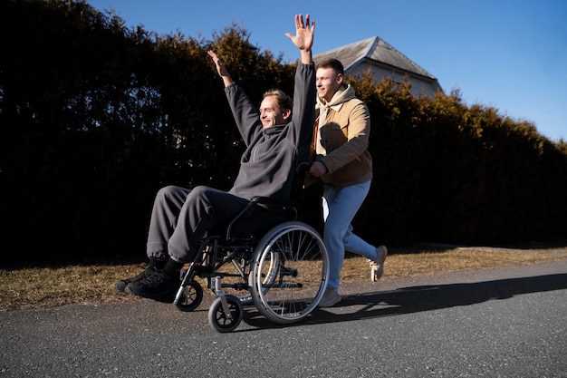 Foto gratuita amigo ayudando a hombre discapacitado sonriente tiro completo