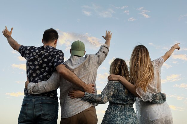Amigos abrazándose en la playa mirando al cielo